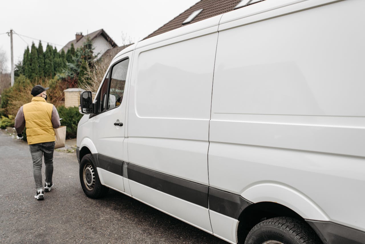 A delivery person carrying a package away from a delivery van outdoors, showcasing efficient logistics.